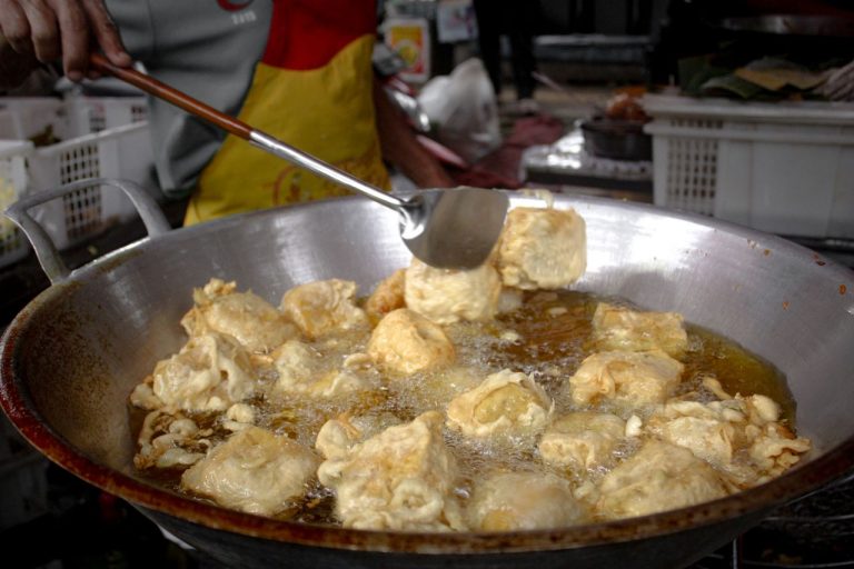 Fried tofu being prepared in a street market for a crispy snack.