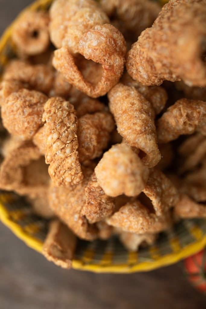 Close-up view of crispy pork cracklings in a bowl, perfect for snack enthusiasts.